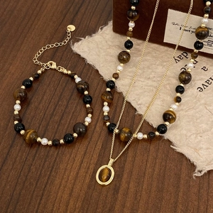 Detailed set of tiger eye stone and pearl necklace with matching bracelet on wood