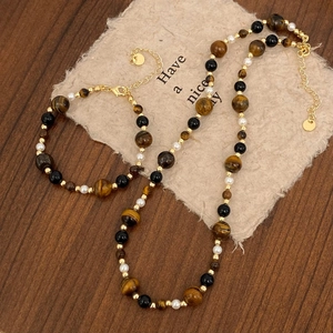 Close-up of tiger eye stone and pearl jewelry set on a rustic wooden tabletop