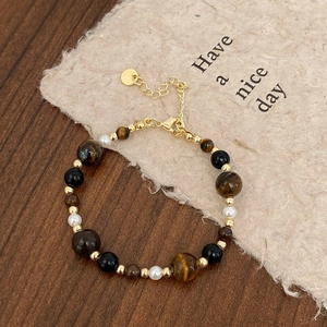 Close-up of tiger eye beads and pearls on an elegant beaded necklace with gold accents