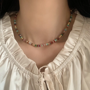 Colorful natural stone beaded necklace with gold spacers worn by model in white blouse