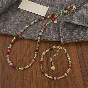 Detail of colorful natural stone necklace and bracelet set on a warm knitted sweater
