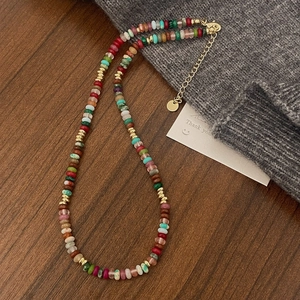 Detail of colorful bohemian stone bead necklace with gold hardware on wooden surface
