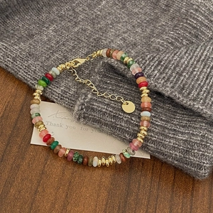 Detail of colorful natural stone beaded necklace with gold metal spacers and lobster clasp