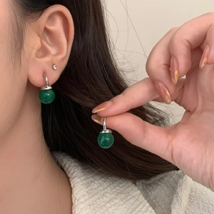 Close-up of green chalcedony drop earrings with silver hooks on model with dark hair