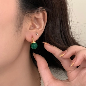 Macro detail of elegant green chalcedony drop earring with gold plating on model