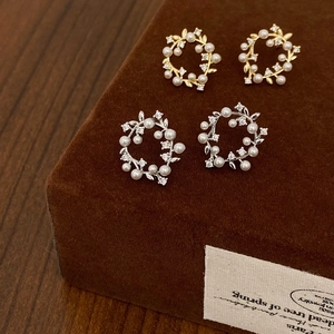 Close-up of vintage wreath pearl earrings in gold and silver finish on a jewelry box