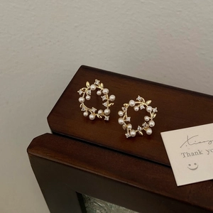 Close-up of vintage gold wreath earrings with pearls and crystals on a wooden surface