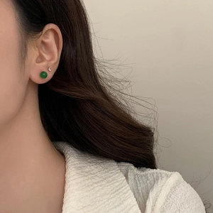 Close-up of green chalcedony stud earrings worn on ear for minimalist style