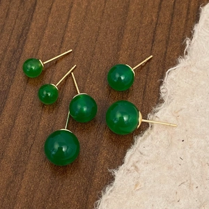 Detailed view of green chalcedony stud earrings in three sizes on a wooden background
