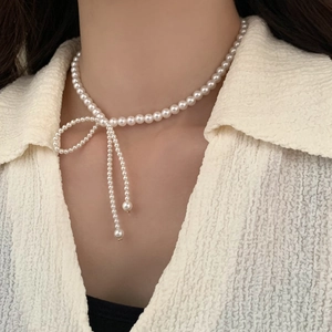 Detail of elegant pearl necklace with bow design and tassel on model's neckline