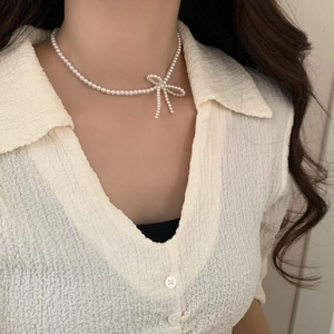 Detail of elegant pearl choker featuring a side-placed pearl bowknot on model neck