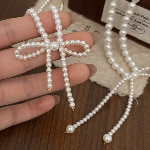 Elegant pearl necklace with a bow pendant displayed on a vintage-style jewelry box
