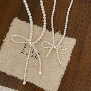 Detail of elegant pearl necklaces with bow pendants and tassels on a rustic paper background