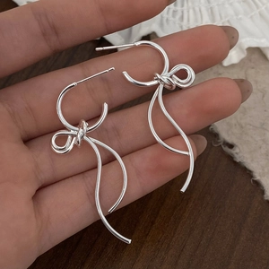 Detailed close-up of a silver bow-knot earring with fluid streamlined metal design