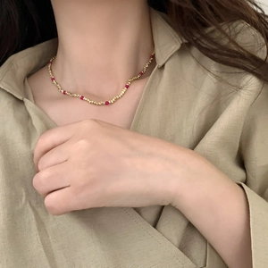 Vue détaillée d'un collier de perles dorées avec des pierres rouges sur un mannequin