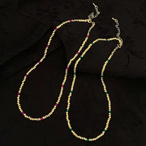 Détails des colliers en perles dorées avec pierres naturelles sur tissu noir