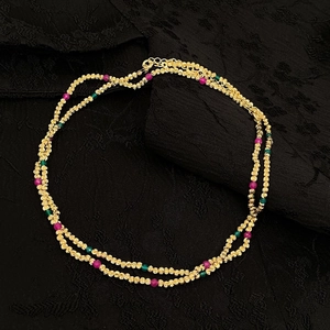 Détail d'un collier à double rangée plaqué or avec des perles en pierres facettées colorées