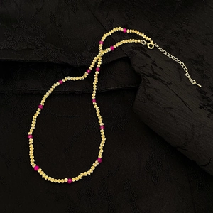 Détail du collier de perles facettées plaqué or et pierres rouges avec fermoir