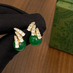 Close-up of vintage gold earrings with sparkling zircons and a round green chalcedony stone