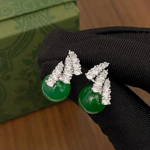 Close-up of silver earrings with sparkling zircon inlay and round green gemstone beads