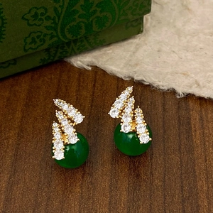 Macro shot of vintage gold earrings with zircon crystals and round green stones