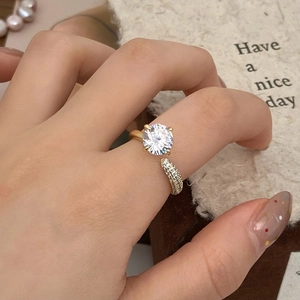 Close-up of gold adjustable ring featuring a large sparkling zircon and micro-pave accents