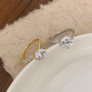 Adjustable gold and silver rings with large round zircon stones on a ceramic plate