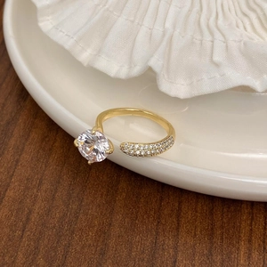 Detail of gold open ring with a large round zircon and sparkling pave diamonds