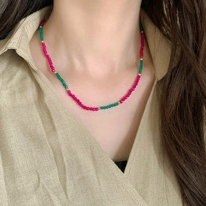 Detail of handmade natural stone necklace with green and rose faceted beads on a model