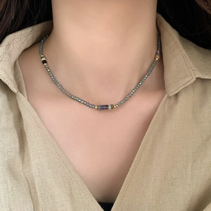 Detail of handmade beaded necklace with faceted grey-blue stones and mixed color accents
