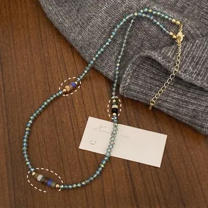 Detailed close-up of handmade beaded necklace with natural stones on a gray knit sweater
