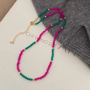 Detail of handmade necklace with magenta and dark green beads and gold lobster clasp