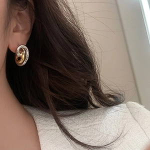 Close-up of interlocking gold and silver dual-tone hoop earrings worn by a model