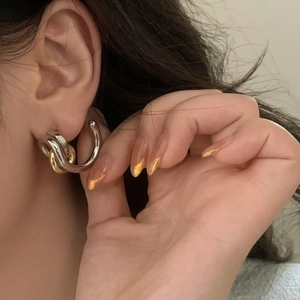 French minimalist gold and silver intertwined geometric hoop earrings on female model
