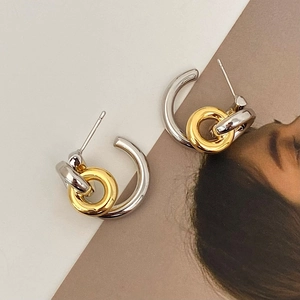 Minimalist interlocking gold and silver geometric hoop earrings on a fashion background