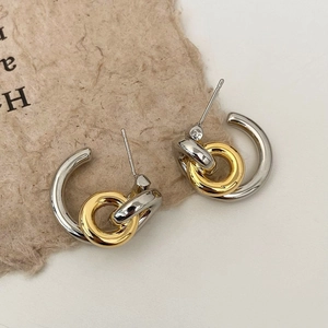 Detail of interlocking gold and silver geometric hoop earrings on a textured paper surface