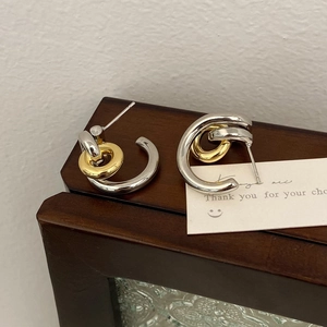 Macro view of French minimalist two-tone silver and gold geometric hoop earrings