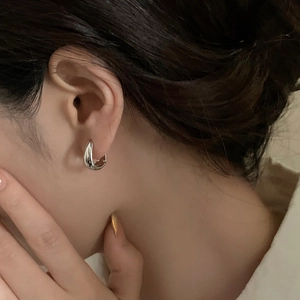 Close-up of a minimalist silver teardrop earring with a polished mirror finish on model