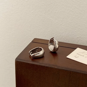 Close-up of polished silver teardrop hoop earrings on a vintage wooden jewelry box