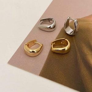 Minimalist U-shaped metal hoop earrings in polished gold and silver finishes on a magazine
