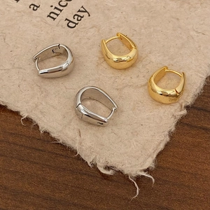 Detail of gold and silver tapered hoop earrings with polished metallic finish