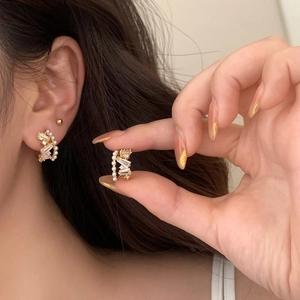Elegant gold earrings with pearls and zircon crystals shown on a model's ear