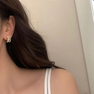 Close-up of elegant gold earrings with white pearls and sparkling cubic zirconia stones