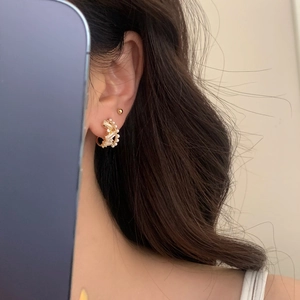 Elegant gold hoop earrings with zircon stones and pearls shown on model's ear