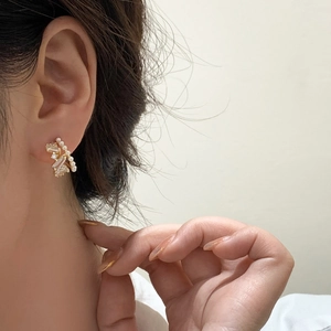 Close-up of gold-plated hoop earring with baguette zircon and a mini pearl on ear