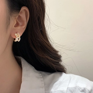 Detail of gold ear cuff featuring rectangular zircons and small white pearls on model