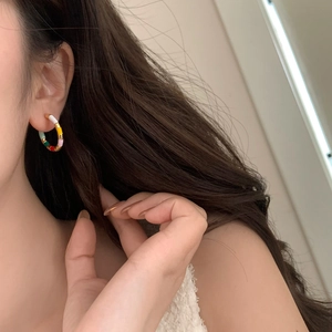 Gros plan de boucles d'oreilles émaillées colorées sur un modèle style bohème