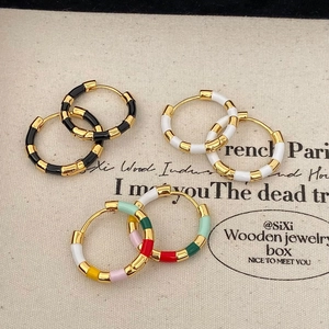 Gros plan de boucles d'oreilles créoles dorées style français avec émail coloré élégant