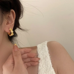 Gros plan sur d'élégantes boucles d'oreilles dorées en C avec zircons sur un mannequin