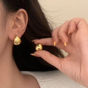Golden teardrop earrings with a brushed metallic finish on a model for a modern look